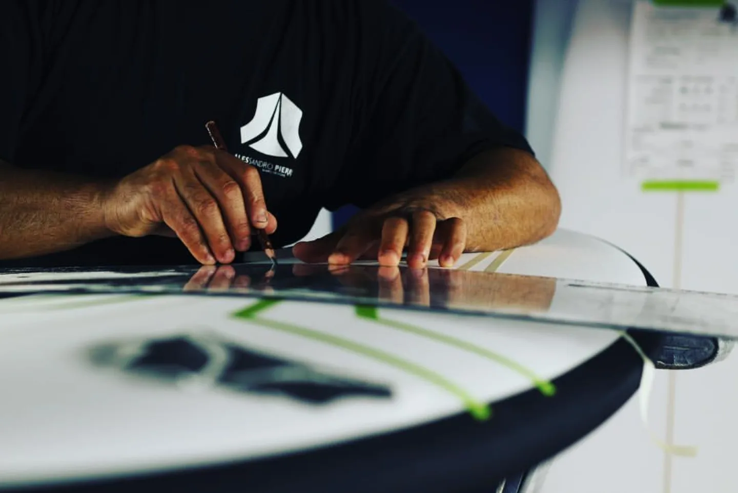 Alessandro Pierre réalisant un artwork personnalisé sur une planche de surf, détail pinstripe