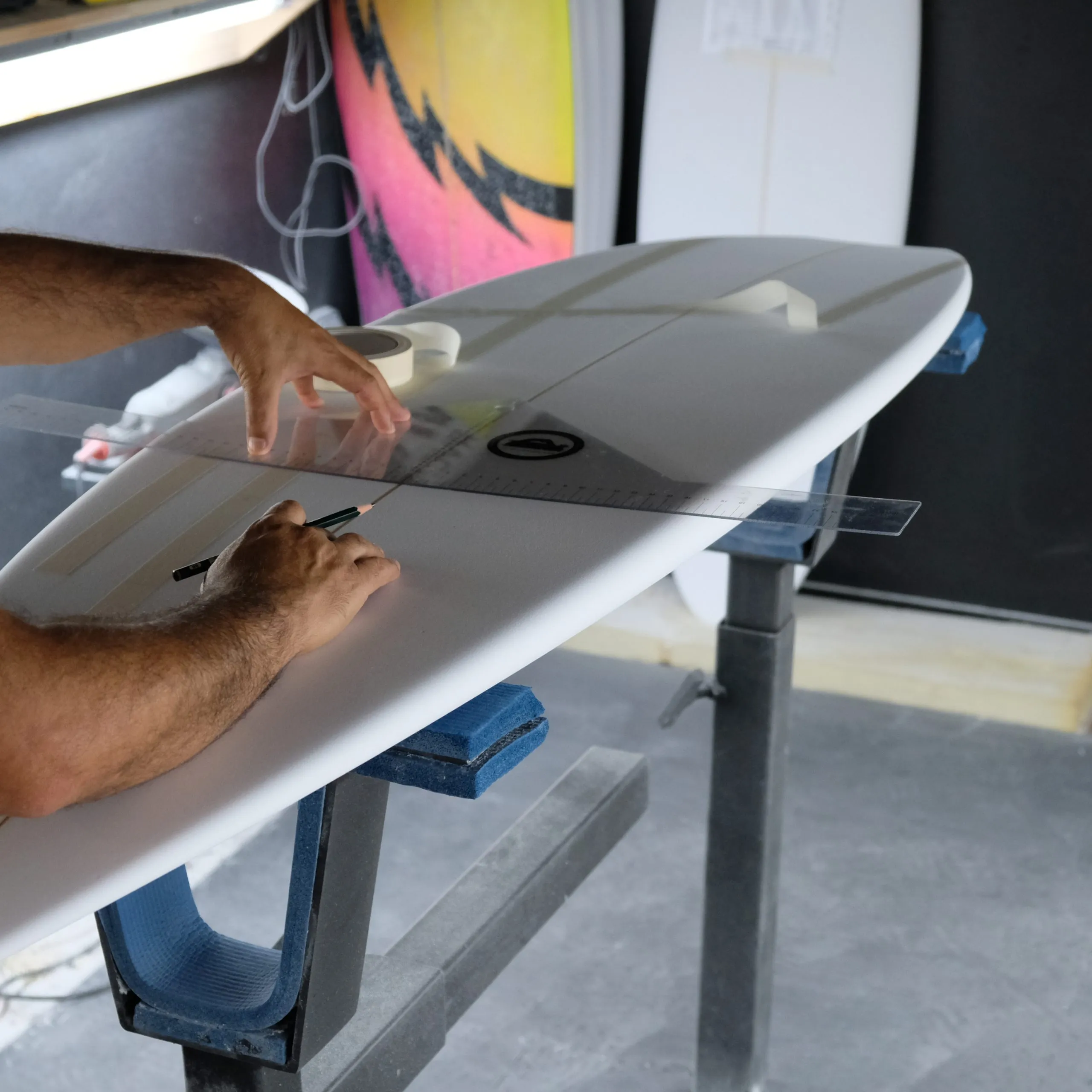 Alessandro Pierre traçant l'outline d'une planche de surf dans son atelier de Seignosse